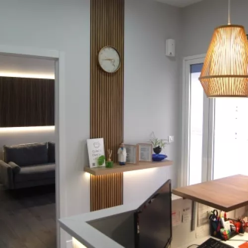 Área de recepción de la clínica con iluminación cálida y detalles en madera