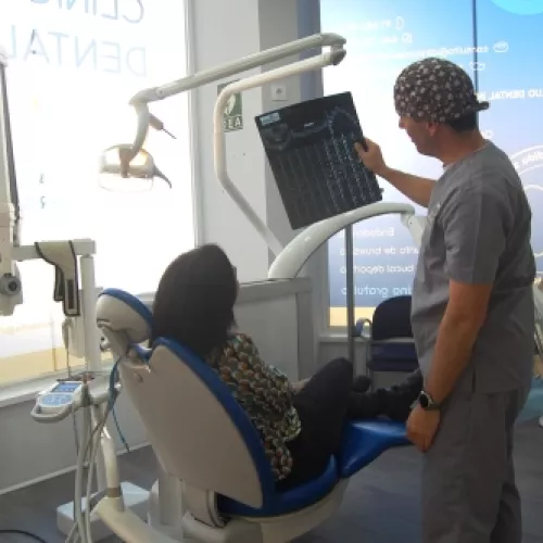 Dentista explicando radiografía a paciente en sillón dental